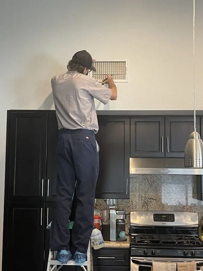 Technician inspecting an air vent during HVAC service in Saks